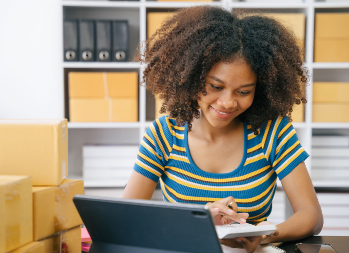 A small business owner using a calculator while creating a pricing strategy.