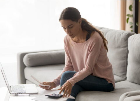 A woman sitting on a sofa and managing her business bills.