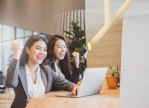 Two businesswomen in suits working with laptop