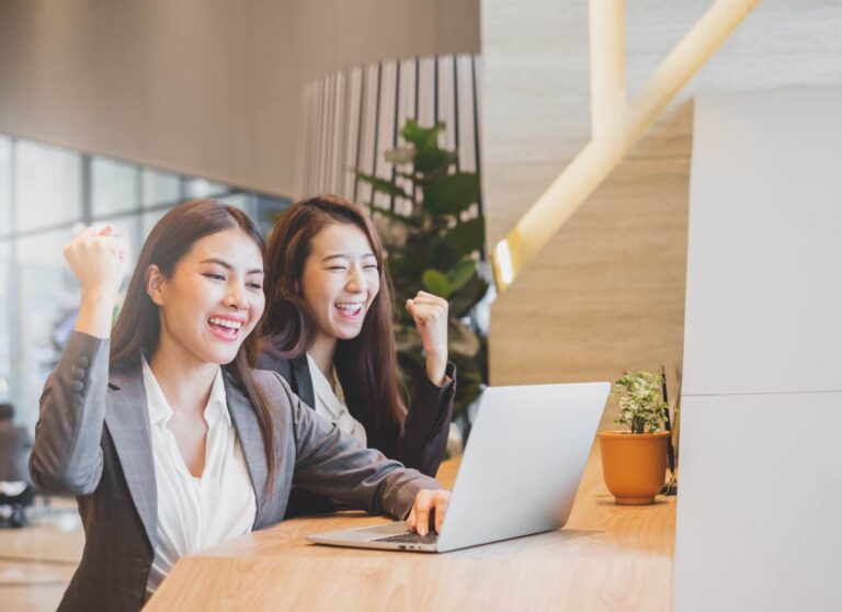 Two businesswomen in suits working with laptop