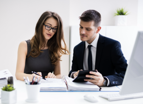 Two Young Businesspeople Calculating Invoice Calculator Stock Photo