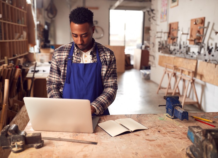 A small business owner sending payments online in his workshop.