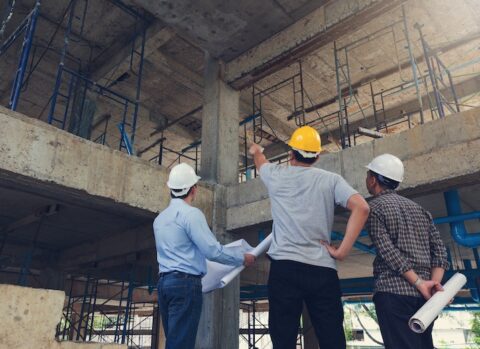Three contractors at a construction site going over plans together.