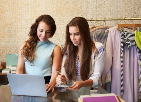 The owners of a fashion boutique using a laptop to set up online payments to suppliers.