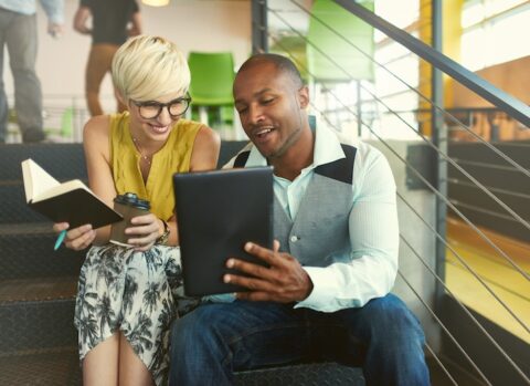 Two young professionals getting inspiration from online business experts.