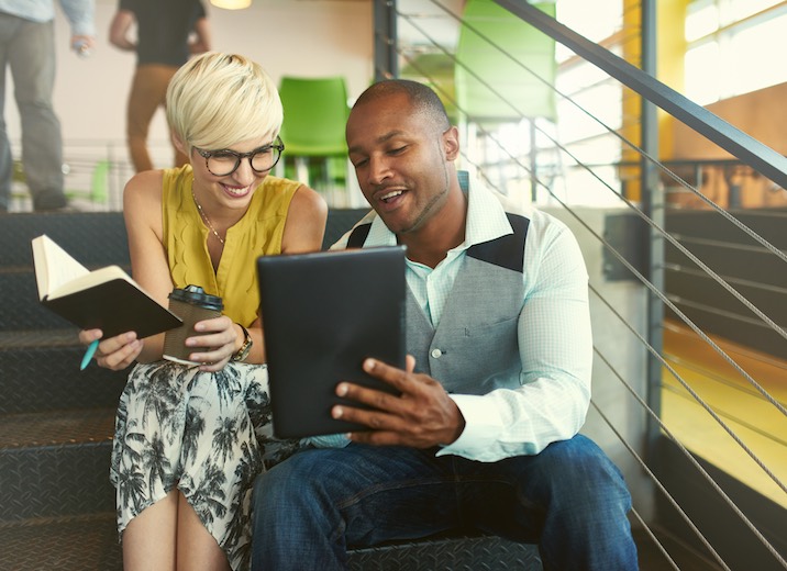 Two young professionals getting inspiration from online business experts.