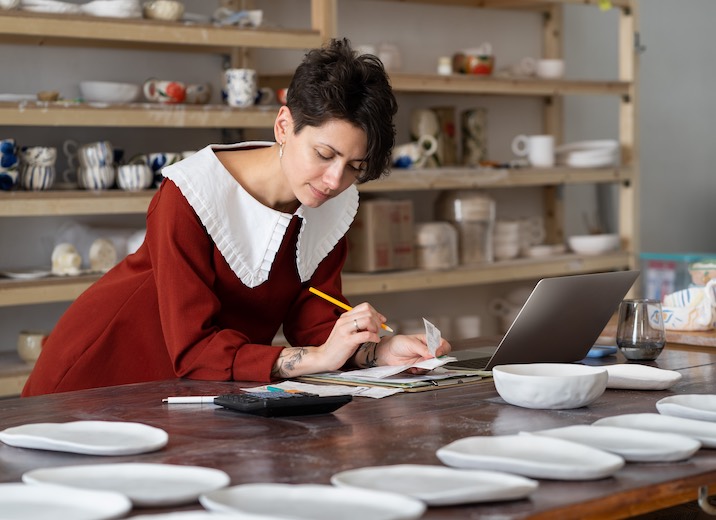 A small business owner organizing invoices and bills in her workshop.