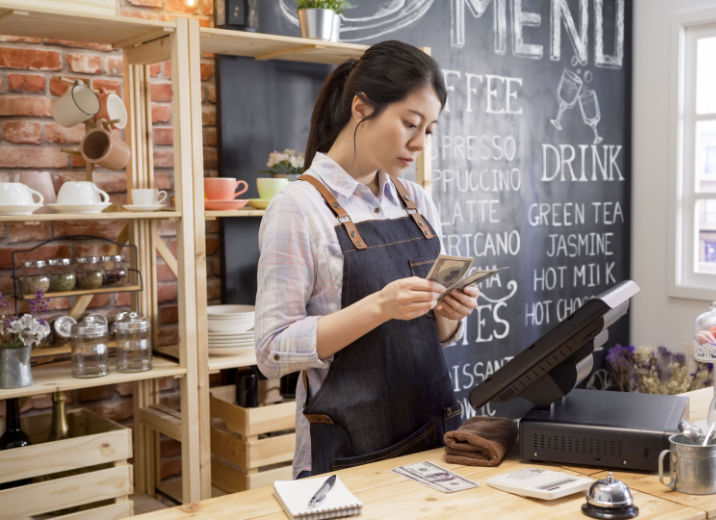 A coffee shop owner setting some cash aside.