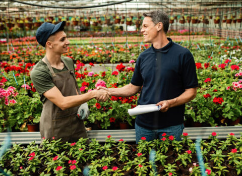 A small business owner shaking hands with his flower vendor.