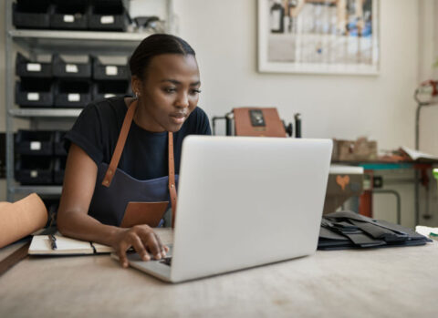 A small retailer reviewing chargeback disputes on a laptop in her back office.