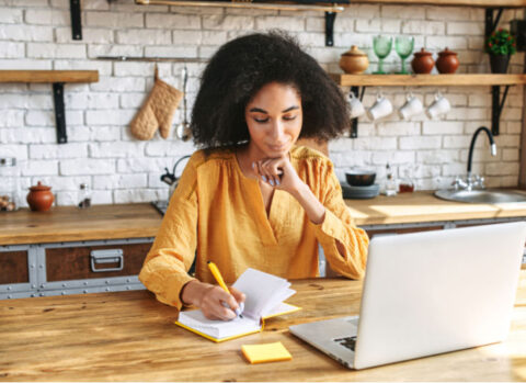 A small business owner focuses on writing in her kitchen.
