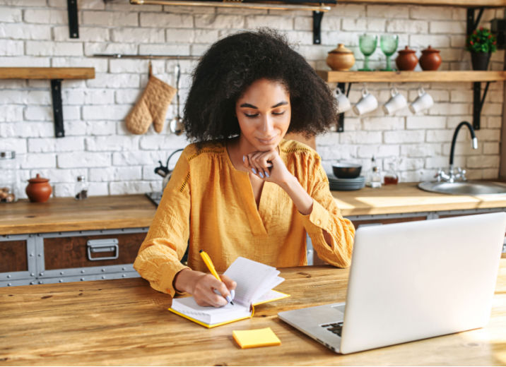 A small business owner focuses on writing in her kitchen.