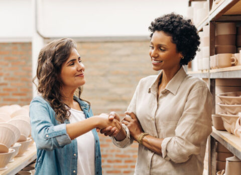 A homeware shop owner shaking hands with her ceramics vendor.