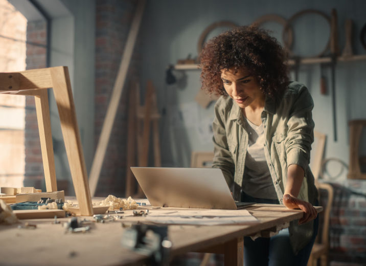 A carpenter sending an ACH payment in her woodshop.