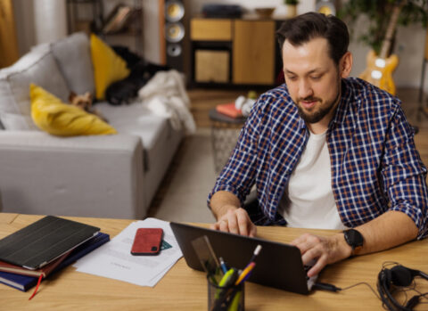 A small business owner in a home office uses cloud accounting software to manage his bookkeeping on his laptop.