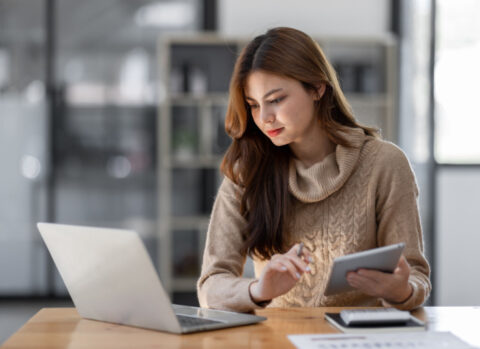 A small business owner using a laptop and tablet to manage AP and AR.