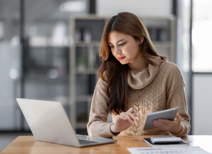 A small business owner using a laptop and tablet to manage AP and AR.