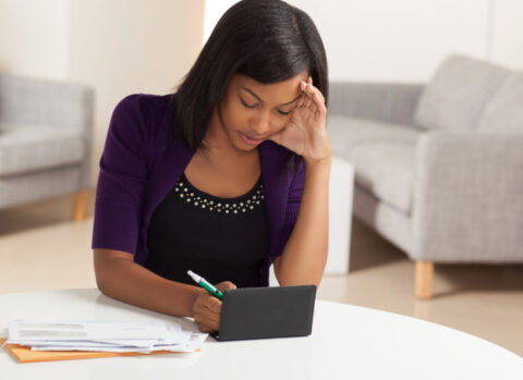 A small business owner writing checks to pay vendors in her living room.