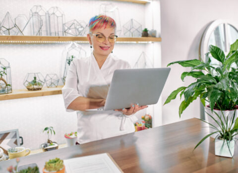 A plant decor shop owner using a laptop to manage accounts payable.