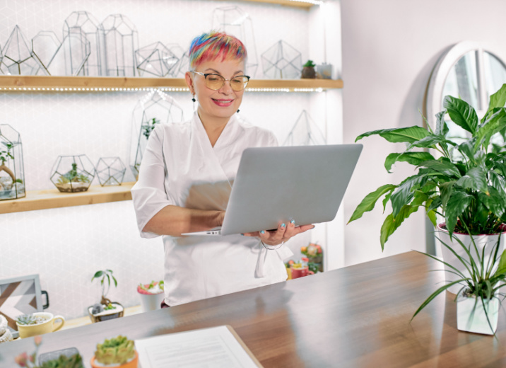 A plant decor shop owner using a laptop to manage accounts payable.
