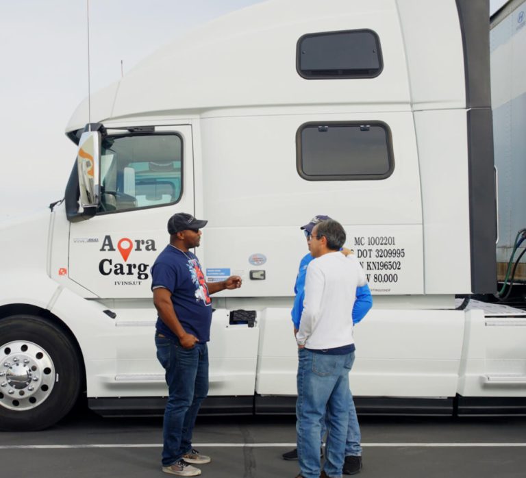 Ignacio Araya, Aora Cargo Founder and CEO standing with two drivers next to a truck.