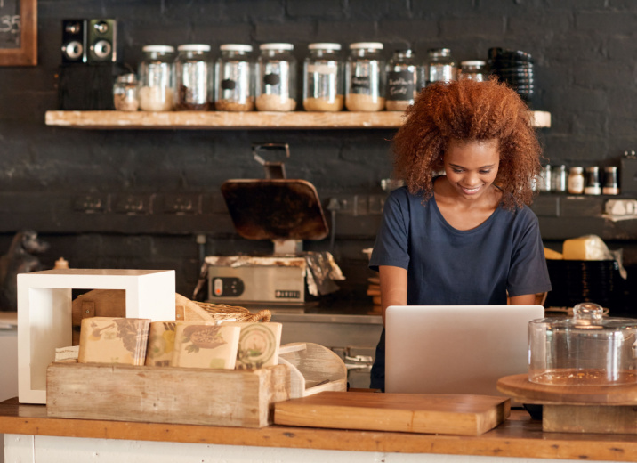 A coffee shop owner uses a laptop to send payments to her international suppliers.