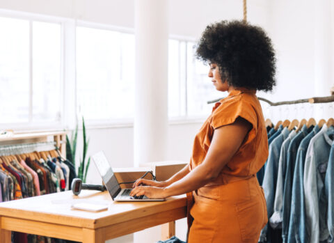 A fashion boutique owner using a laptop to send online payments to vendors.
