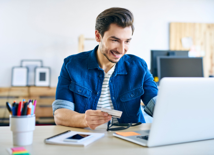 A web designer uses a laptop to pay bills online with a credit card.