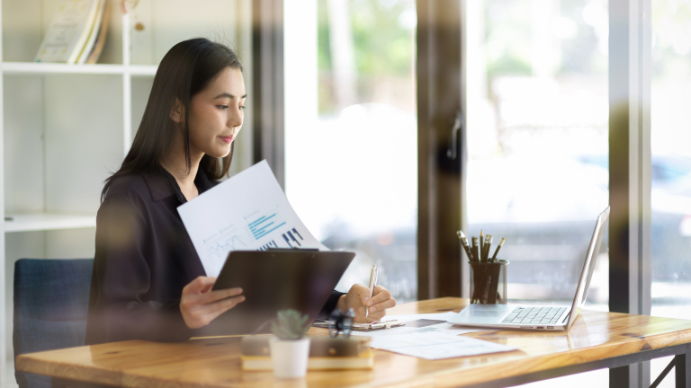 Business owner reviewing accounts payable reports and cash flow data at desk, analyzing financial charts and invoice processing metrics