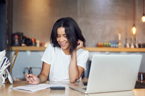 Small business owner managing finances and profit allocation at home office, reviewing cash flow with laptop, calculator, and financial documents