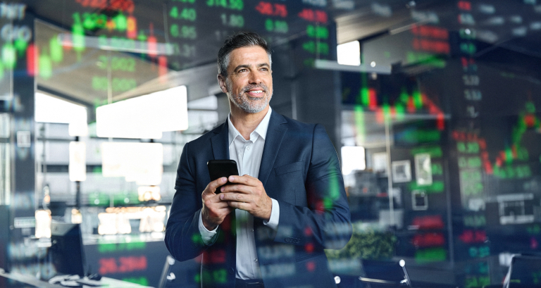 Business executive monitoring cash flow forecasting data and financial projections on real-time trading screens while using mobile financial management tools